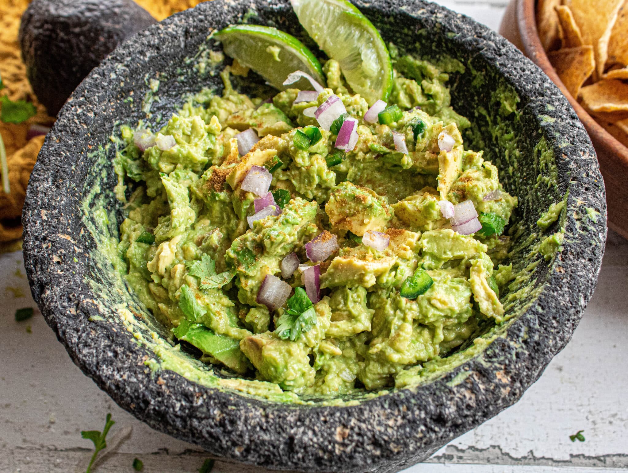 Guacamole with red onions, jalapenoes, cumin, lime in a Molcajete Bowl.