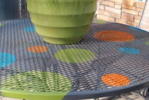 Repainted wrought iron patio table and chairs with stenciled polka dots.