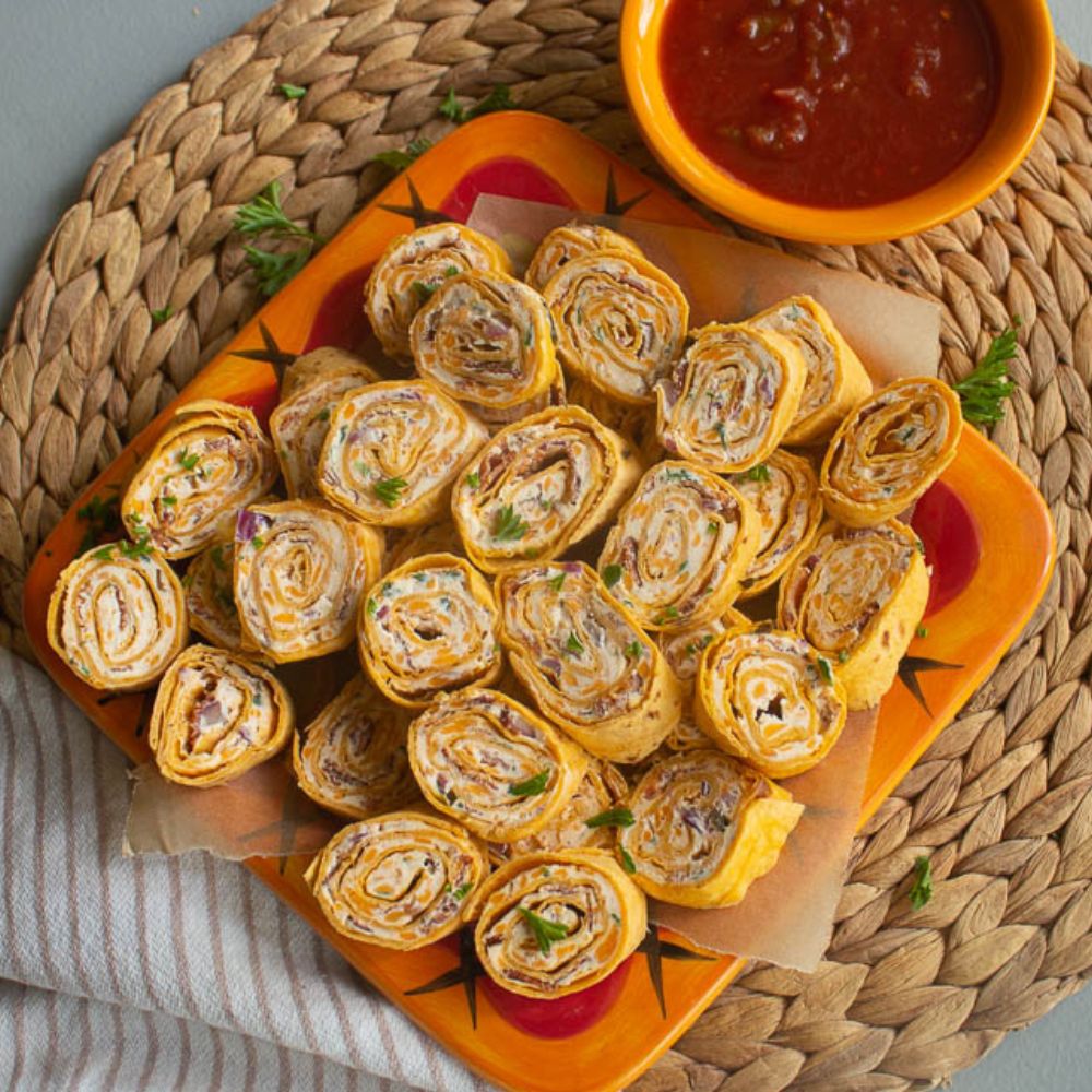 Spicy Bacon Ranch pinwheels on an orange plate served with picante salsa.