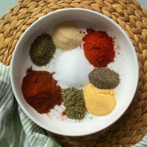 8 spice ingredients in a white bowl on a tan bamboo mat.