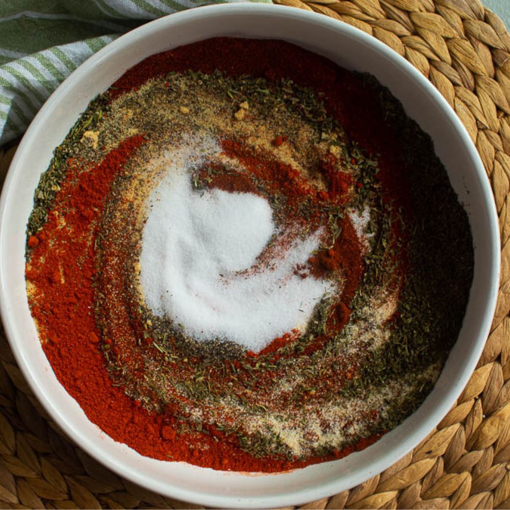 White bowl full of 8 different spices to make Cajun seasoning.