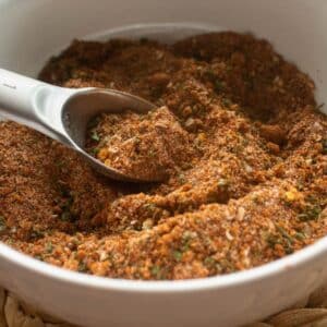 White Bowl full of homemade sweet and spicy jerk seasoning with a tablespoon as a scoop.