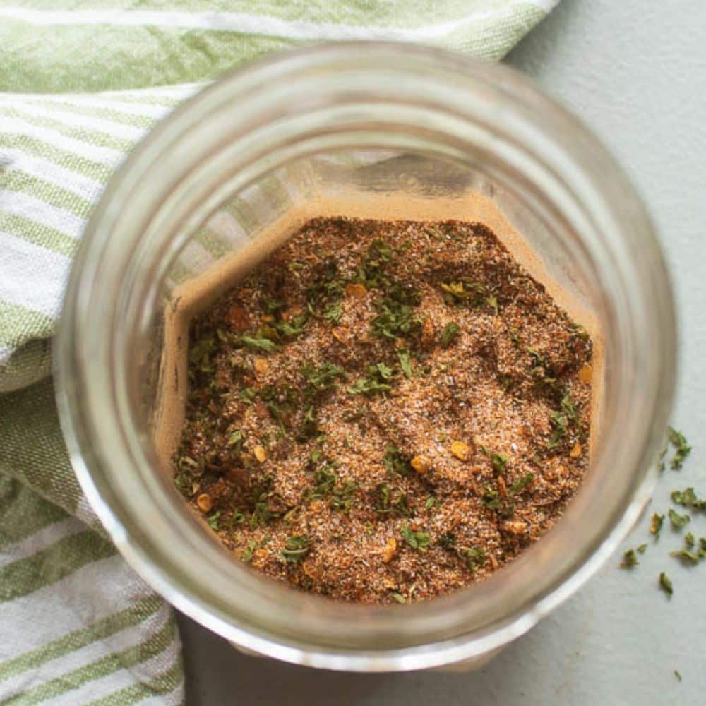 Homemade Jerk Seasoning in a mason jar with a green and white towel.